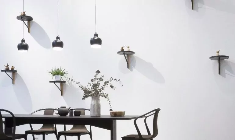 Salle à manger avec table en bois, suspensions noires et fleurs